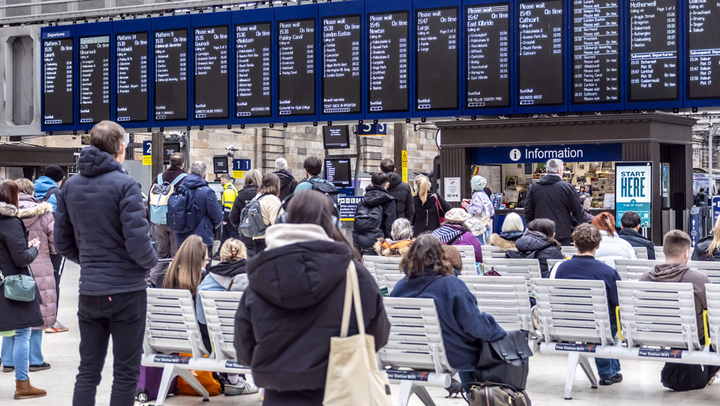 People viewing a departure board at Glasgow Central railway station