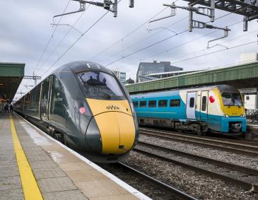 An image of a Great Western Railway and a Transport for Wales train stopped at a station.