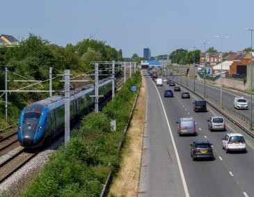 A train on the tracks with cars on the side